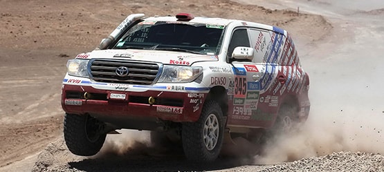 Toyota Land Cruiser, exterior sports car, front side view, driving rapidly through a desert, daytime background